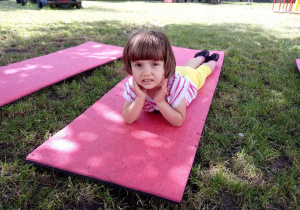 Dziewczynka odpoczywa na macie na trawie